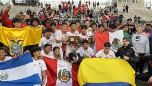 Crowd of players posing for photo with flags of multiple nations on display. Player in the middle holds plaque